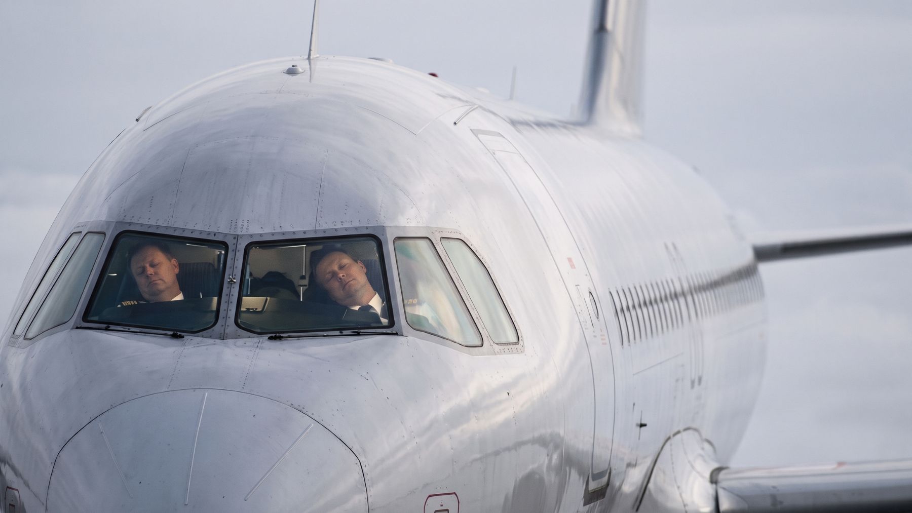 Both pilots slumped asleep behind a cruising A320 cockpit window