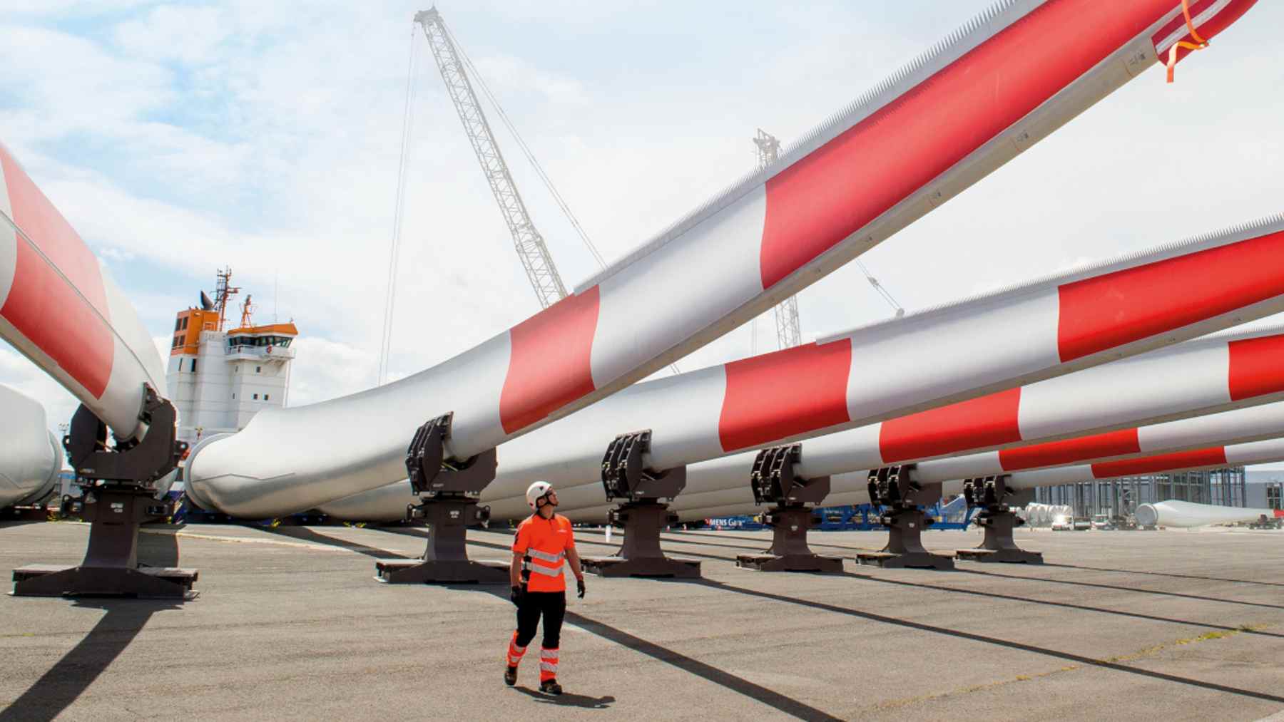 Three turbines spin off Heligoland with blades built to dissolve in an acid bath, which frees the glass fiber and wood sealed inside 1 Worker examines a recyclable wind turbine blade seam dissolving at a dockside, three turbines spin