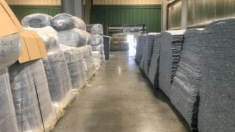 Shredded denim insulation fiber falling into a hopper at a recycling plant, jeans goes onto